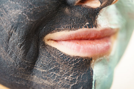 Woman cleaning skin face, using green mud and carbon black mask. Girl taking care of oily complexion. Beauty and kincare.の写真素材