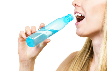 Smiling woman holding bottle of liquid cosmetic, having fun, enjoying morning routine procedure for skincare. Beauty therapy concept.の写真素材