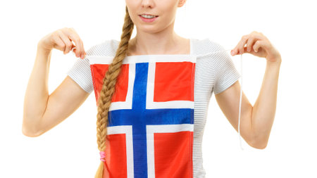 Blonde female student holding Norwegian flag on her chest. Travel and education. Learning foreign languages.の写真素材