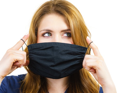 Woman using black protective reusable face mask, covering mouth. Coronavirus prevention. Health and safety.の写真素材