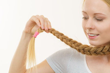 Blonde girl with long braid hair. Haircare, popular hairstyle.の写真素材