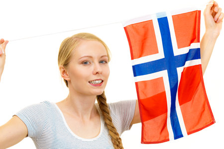 Blonde teenage girl holding flag of Norway. Education. Norwegian language school. Visit Norway concept.の写真素材