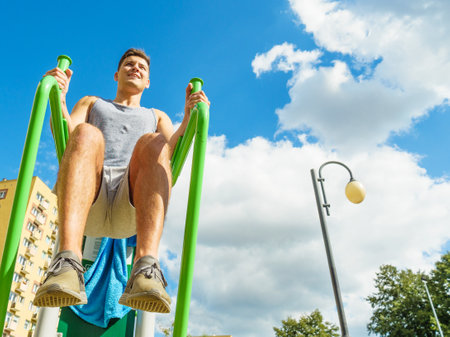 Young man doing exercises on the public gym equipment in the open air.の写真素材