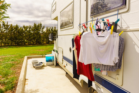 Clothes clean washing laundry hanging to dry on clothesline outdoor at caravan. Bowls and wash machine in the background. Camping, vacation trip.の写真素材