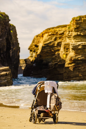 Baby stroller outdoors on sea shore. Cathedral Beach in Galicia Spain. Family vacation.の写真素材