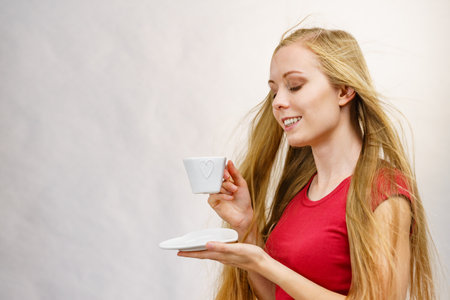 Blonde long hair woman with heart shaped coffee cup. Time to wake up, switching on. copy space.の写真素材