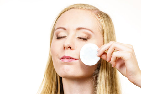 skincare. Young woman cleaning her skin face with cotton pad. Female removing makeup, using facial micellar water.の写真素材