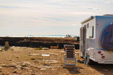 Camper, recreational vehicle and chairs on mediterranean rocky coast in Spain. Camping on the...