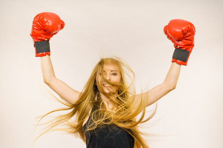 Blonde long hair woman wearing big red gloves standing with arms up, celebrating success. Female fight for equal rights for women.. Gender equality concept.の写真素材