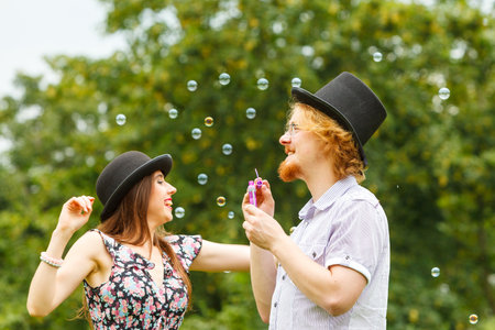 Happiness and carefree concept. Young woman and man having fun blowing soap bubbles together on nature.の写真素材