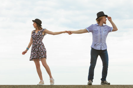 Couple turned away from each other while holding hands. Sad young male and female pulls in different directions. Concept of disagreement, misunderstanding, separation, crisis in relationshipの写真素材