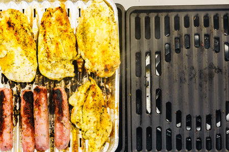 Close up delicious chicken meat and sausages grilling on barbecue gas grill. Barbeque dinner outdoor. Top viewの写真素材