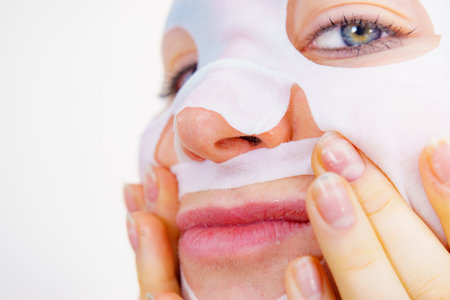 Woman with sheet mask on her face. Girl taking care of skin. Beauty treatment. Skincare.の写真素材