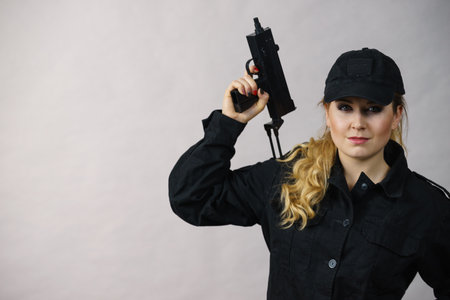 Woman holds automatic gun in hands. Army, weapon.の写真素材