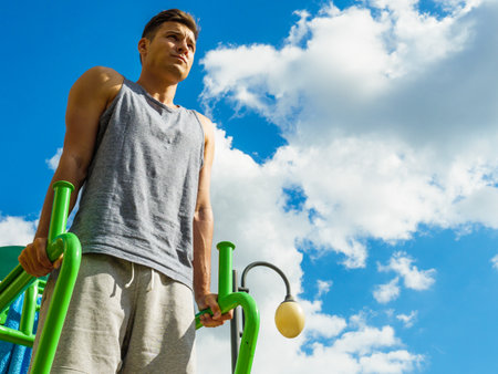 Young man doing exercises on the public gym equipment in the open air.の写真素材