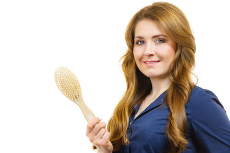 Young woman brushing long healthy brown hair, using hairbrush. Haircare.の写真素材