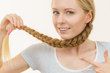 Blonde girl with long braid hair. Haircare, popular hairstyle.の写真素材