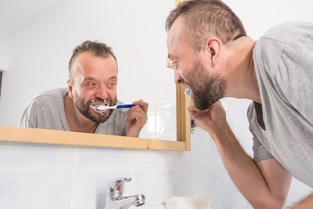 Funnny guy taking care of his oral hygiene, brushing teeth during morning bathroom routine.の写真素材