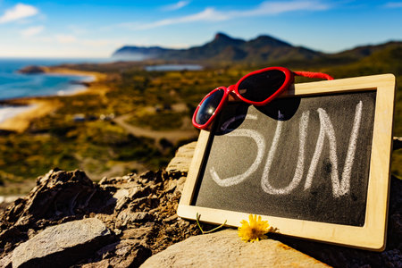Black board with word sun against spanish sea coast. Landscape of Calblanque Park in Murcia Spain. Travel, vacation and prevention of vitamin D deficiency.の写真素材