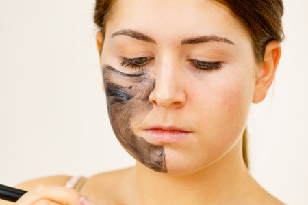 Woman being applying clay carbo detox mask to her face, using brush accessory. Beauty treatment. Skincare.の写真素材