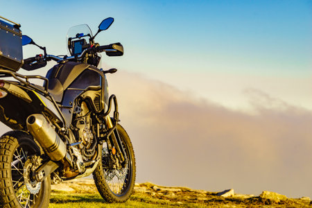 Motorcycle on mountain top above clouds.