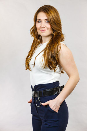 Business woman long wavy hair wearing suit, blue high waist pants with black leather trouser belt.の写真素材