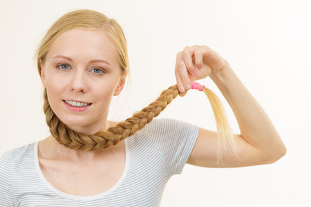 Blonde girl with long braid hair around the neck. Haircare, hairstyling.