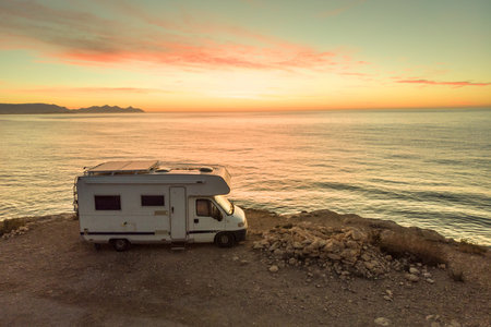 Camper car rv camping on coast sea shore at sunrise. Adventure, traveling with mobile home.の写真素材