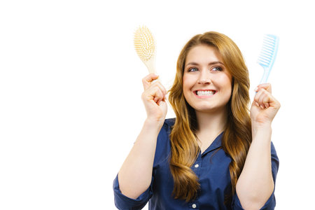 Haircut coiffure haircare concept. Woman with long brown wavy hair holding brush and comb.の写真素材