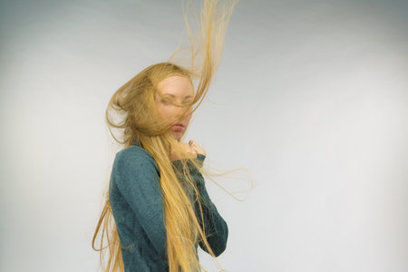 Sad melancholy young woman with blowing long blonde hair.の写真素材
