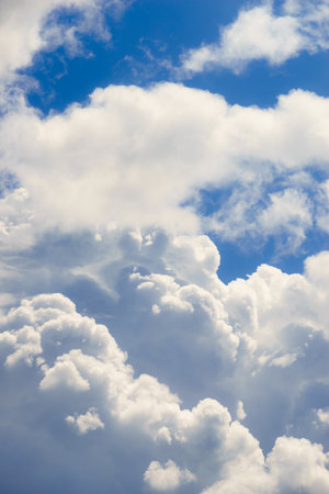 Big white clouds on beautiful blue sky during summertime weather with sunlight.