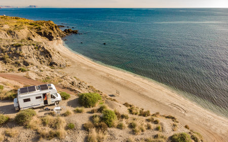 Aerial view. Caravan with solar photovoltaic panels on roof camping on cliff sea coast. Mediterranean region of Villaricos, Almeria, eastern Andalusia, Spain.の写真素材