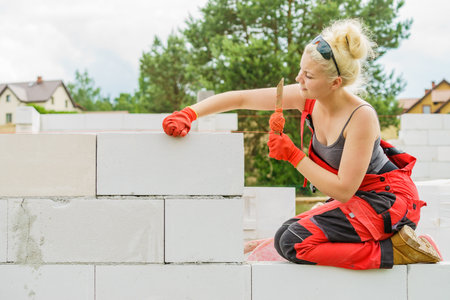 Woman builder using string as level in wall construction. Bricklayer, new house in progress.の写真素材