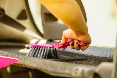 Woman cleaning car interior, using broomの写真素材