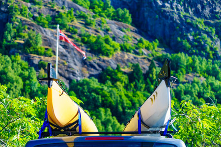 Active lifestyle sports concept. Car with two canoes on top roof in green norwegian mountains.の写真素材