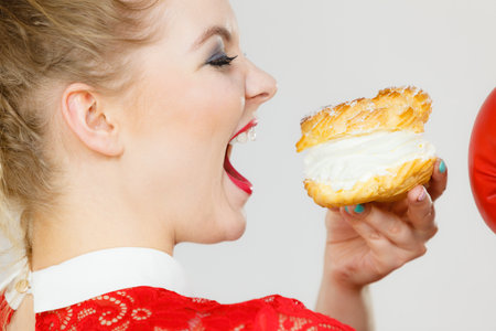 Sweet food and happiness concept. Funny joyful blonde woman holding yummy choux puff cake with...