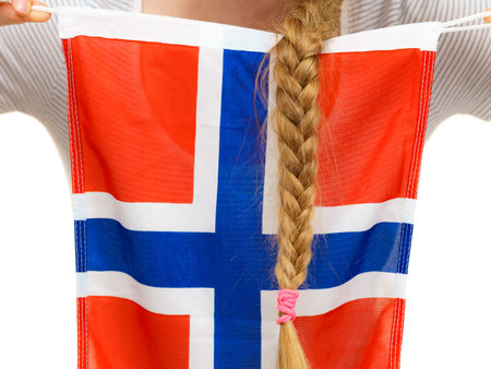 Blonde student girl unrecognizable young woman with long hair braid holding norwegian flag, close up. Education and travel.の写真素材