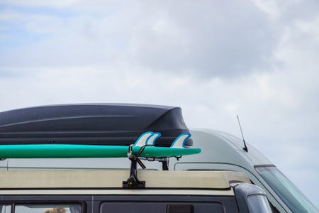 Car equipped with surfboard and trunk or cargo box on roof. Activity, holidays trip. Accessories for...