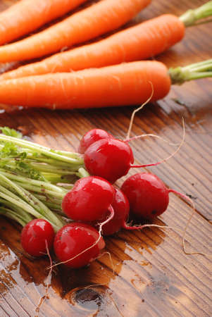 bunch of radishes with carrots in the backgroundの写真素材