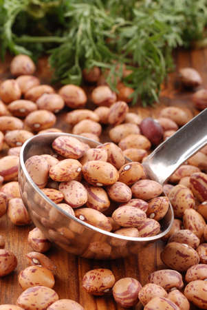beans in a ladle of steel with vegetables in the background