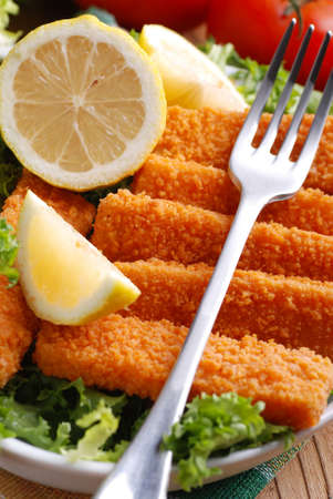 crispy fish sticks with vegetables and lemon slicesの写真素材