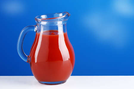 tomato juice in the jug on white table with blue sky backgroundの写真素材