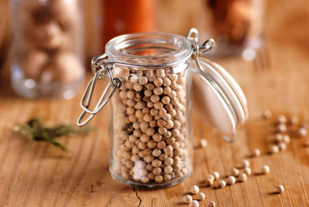 white pepper in glass jar on wooden tableの写真素材