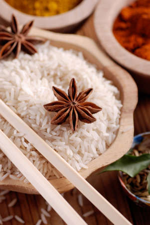 Basmati rice in wooden bowl with other ingredients aroundの写真素材