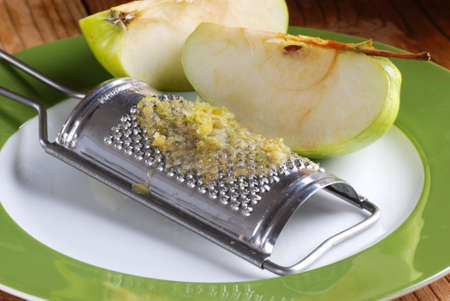 grated apple with tool stainless on wood tableの写真素材