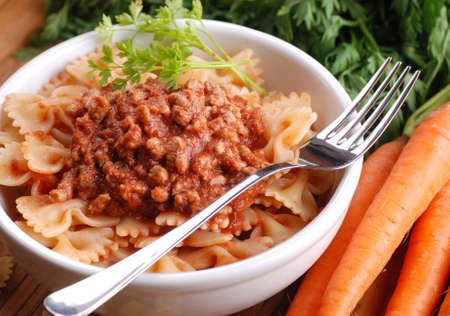 Pasta Bolognese in a bowl with ingredients aroundの写真素材