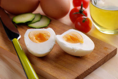 boiled egg cut in half on wooden chopping board