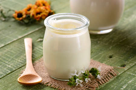 white yogurt in glass jar on green table for breakfast