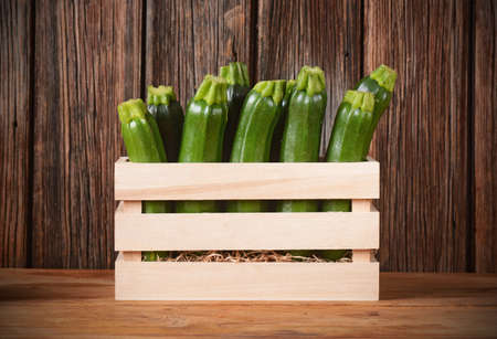zucchini in a wooden box on the tableの写真素材