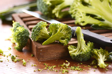 green raw broccoli on wooden chopping boardの写真素材